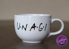 a white coffee cup with the word unagli written on it and dots in black ink