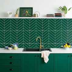 a kitchen with green cabinets and tile backsplash, gold faucet in the middle