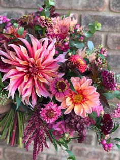 a bouquet of pink flowers sitting in front of a brick wall