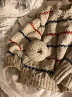 an unmade sweater and ball of yarn on a bed