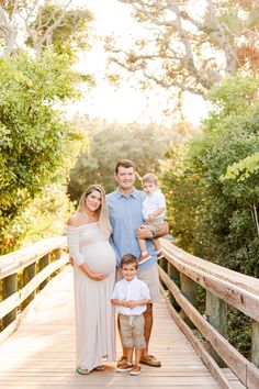 a pregnant couple and their son pose on a bridge