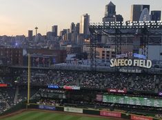 a baseball stadium filled with lots of people sitting in the bleachers at sunset