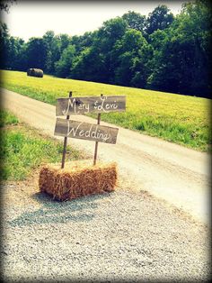 a hay bale sitting on the side of a dirt road next to a field