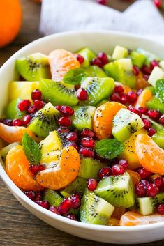 fruit salad with oranges, kiwi and pomegranate in a white bowl