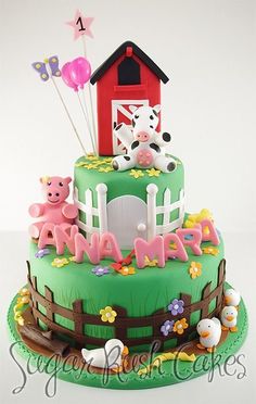 a birthday cake decorated with farm animals and balloons