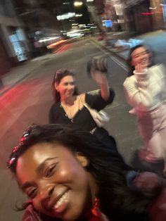 three women are standing on the street and smiling