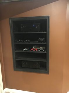 there is a display case in the wall with remotes and other items on it