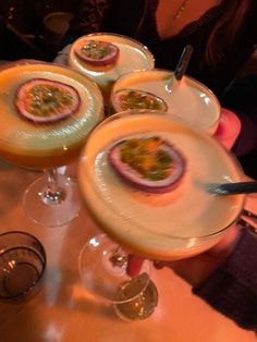 four desserts are sitting on the table in front of two wine glasses and a woman