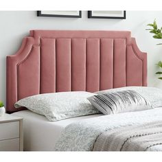 a pink headboard on a white bed with pillows and plants in vases next to it