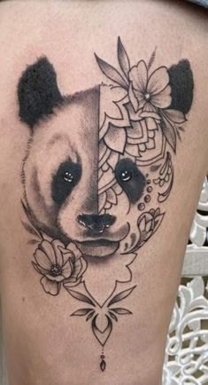 a panda bear tattoo on the back of a woman's thigh, with flowers and leaves