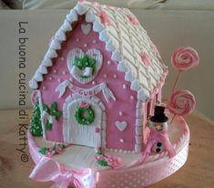 a pink and white decorated house with candy canes on the table next to it