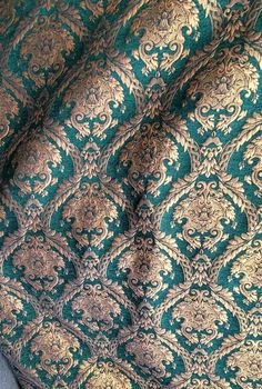 a green and gold patterned fabric with an intricate design on the bottom half of it