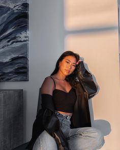 a woman is sitting on the floor with her hand in her hair and wearing jeans