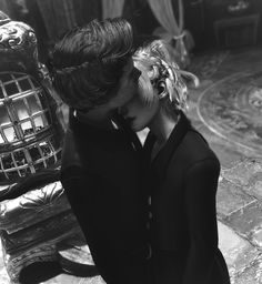 black and white photograph of a man and woman embracing each other in front of an ornate chair