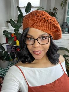 a woman wearing glasses and a knitted hat in front of a potted plant