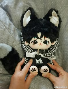 a hand holding a black and white stuffed animal