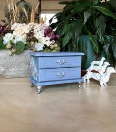 two blue dressers sitting on top of a wooden floor next to potted plants