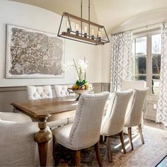 a dining room table with white chairs and a chandelier hanging from the ceiling