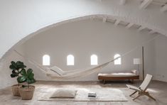 a hammock hanging from the ceiling in a room with white walls and windows