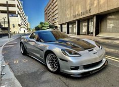 a silver sports car is parked on the side of the road in front of a building