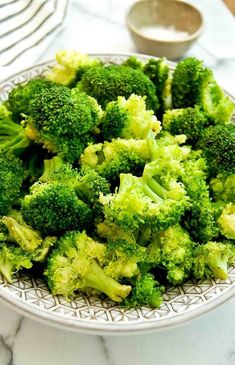 a plate full of broccoli on a marble table