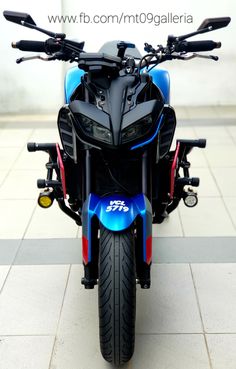 a blue and black motorcycle parked on top of a tile floor