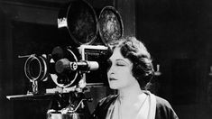 a black and white photo of a woman standing in front of a camera