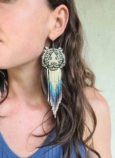 a close up of a person wearing earrings with an owl design on the front and back