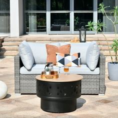 a couch sitting on top of a patio next to a table and potted plant