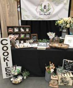 the table is covered with cookies and desserts for sale at the booth where people are selling their goods