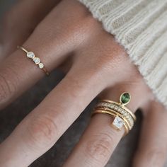 a woman's hand with three different rings on top of her fingers and two diamonds in the middle