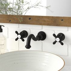 a bathroom sink with three faucets and soap dispenser on the wall