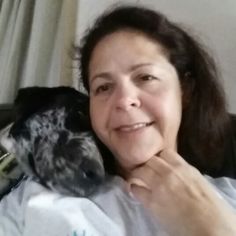 a woman laying in bed with a bird on her arm and smiling at the camera