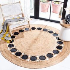 a round rug with black circles on the floor next to a chair and potted plant