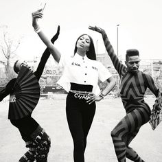 three people in striped outfits are dancing on the street with their hands up and one is holding her head