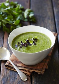 a white bowl filled with green soup on top of a wooden table