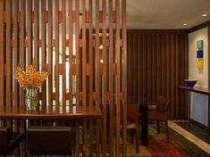 a room divider made out of wooden slats with flowers in a vase on the table