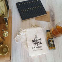 a table topped with glasses and bottles of alcohol next to a wooden tray filled with liquor