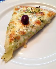 a slice of pizza on a white plate with a black cherry in the middle,