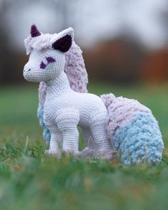 a crocheted toy horse sitting in the grass