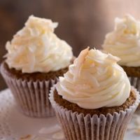 three cupcakes with white frosting on a doily