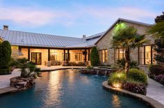 a house with a swimming pool in the front yard and landscaping around it at dusk