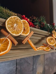 orange slices and cinnamon sticks are arranged on a mantel with christmas decorations around them