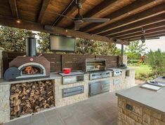 an outdoor kitchen with grill and television on the wall, built in to the roof