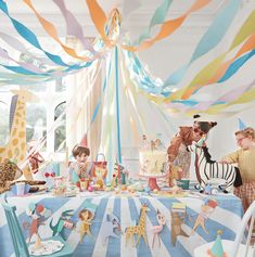 children are gathered around a birthday party with giraffes and zebras on the table