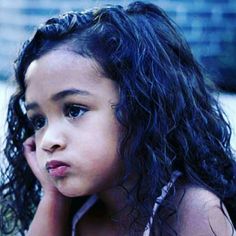 a close up of a child holding a cell phone to her ear and looking off into the distance