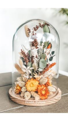 a glass dome with dried flowers under it