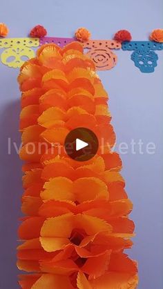 an orange flower lei is hanging from the ceiling with pom poms on it