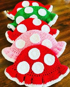 three crocheted mushroom hats sitting on top of a wooden floor