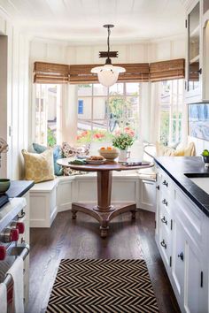 a kitchen with white cabinets and black counter tops in front of a bay window filled with windows